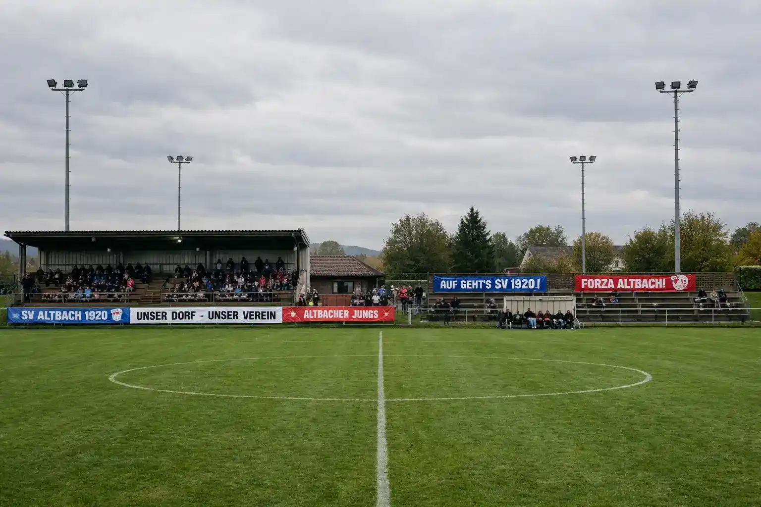 Kleines Fu&szlig;ballstadion einer unteren Liga mit wenigen Zuschauern auf den Trib&uuml;nen bei Tageslicht